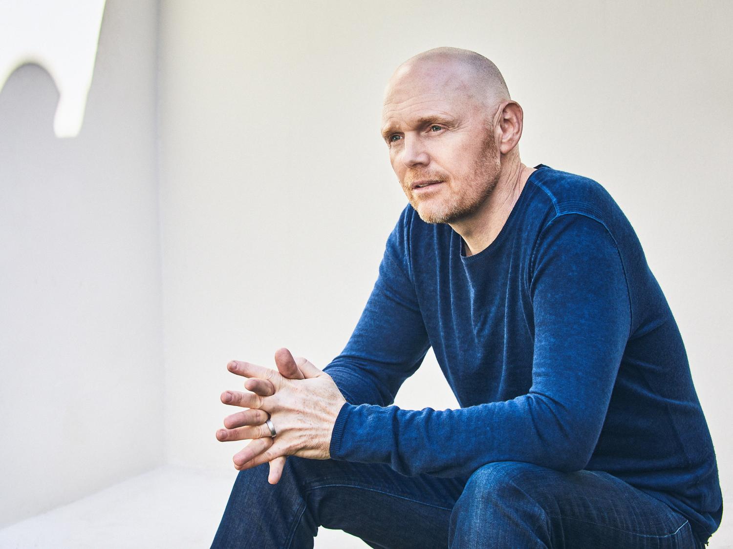 Photo of Bill Burr wearing blue jeans and a blue shirt on a white background