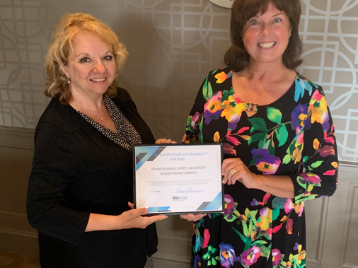 Two women hold up certificate at ceremony