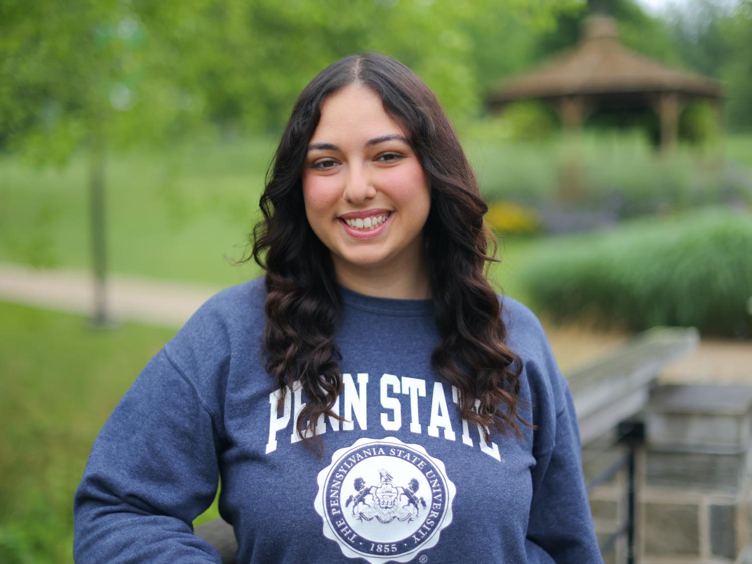 woman wearing blue Penn State sweatshirt leaning on a bridge