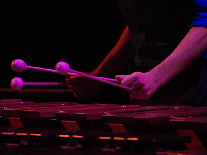 Stage performance shot of hands holding mallets above a xylophone. 