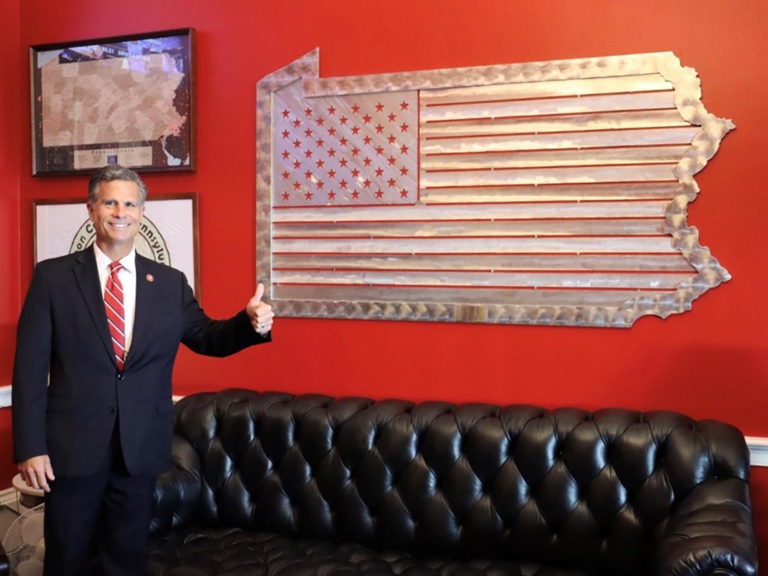 A large metal flag of Pennsylvania hanging on a red office wall