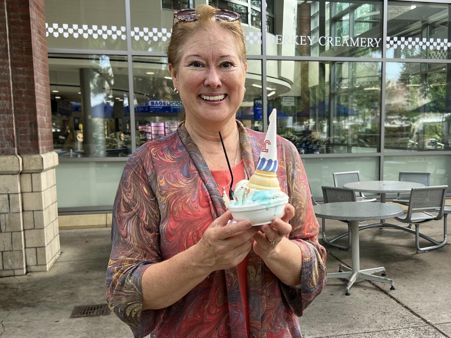 Renata Engel holds a dish of ice cream that as cone on top of it. She's standing in front of the Berkey Creamery.