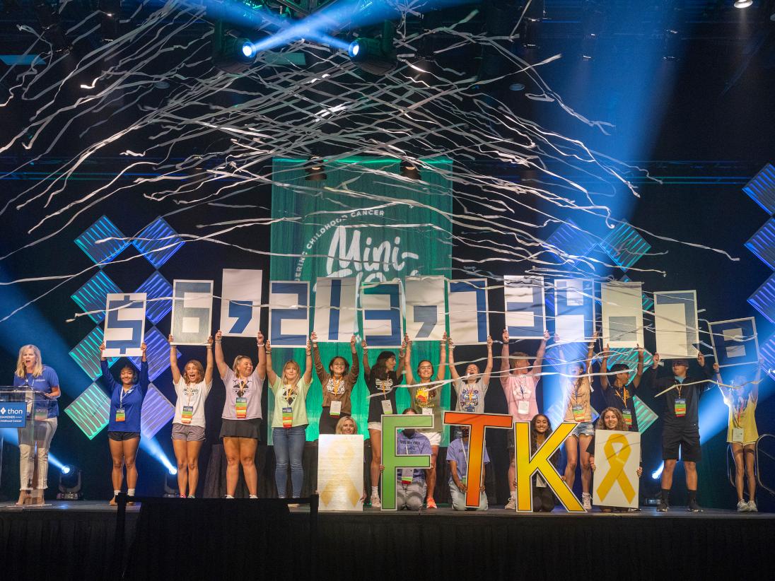 A group of high school students hold up signs showing more than $6 million dollars raised 