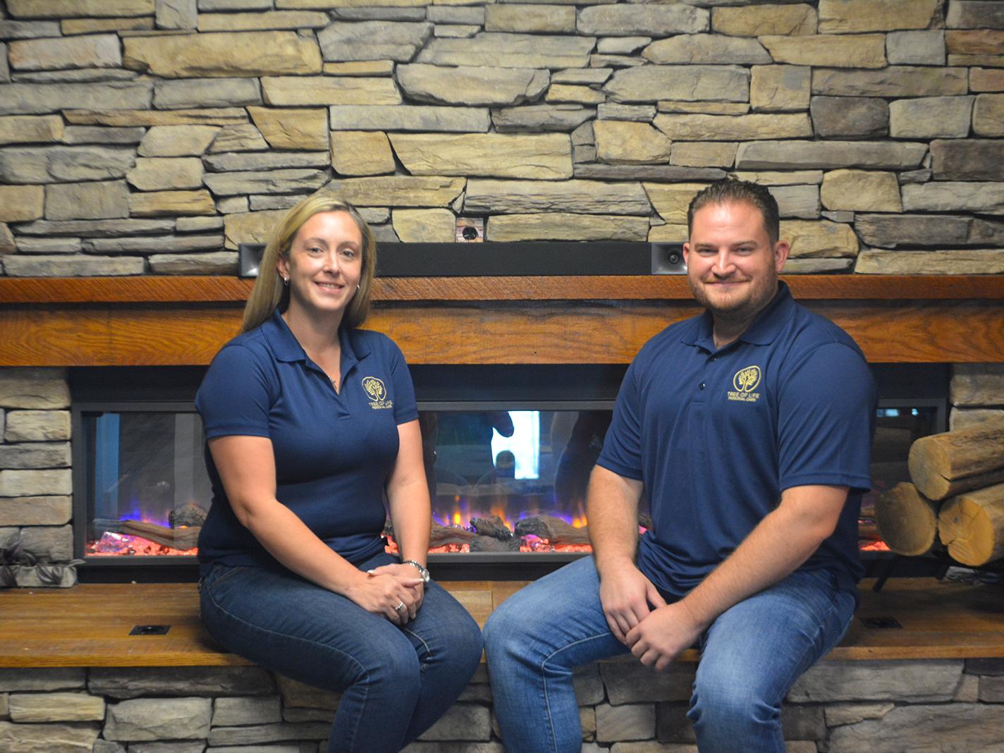 Adult woman and man sittingin front of a stone fireplace