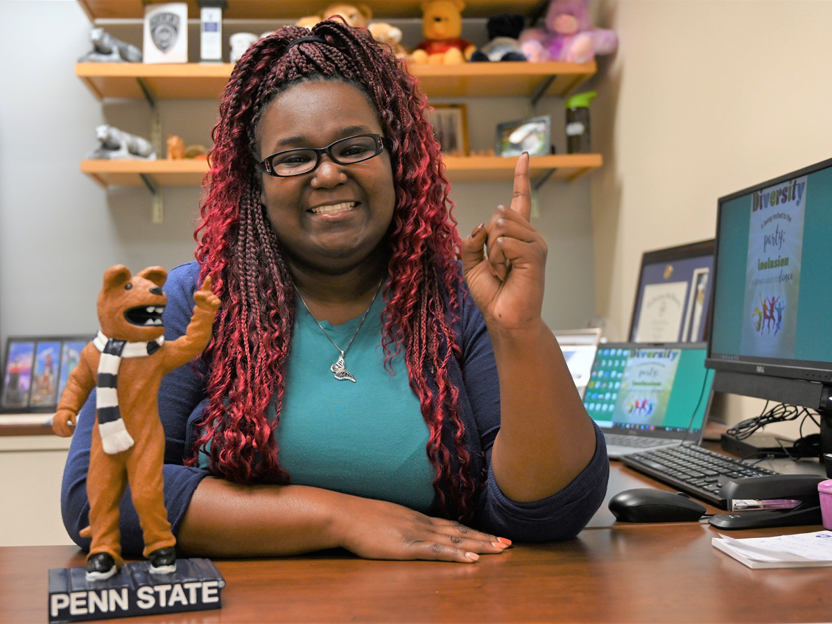 Iris Richardson sits at her desk modeling a Nittany Lion sculpture.
