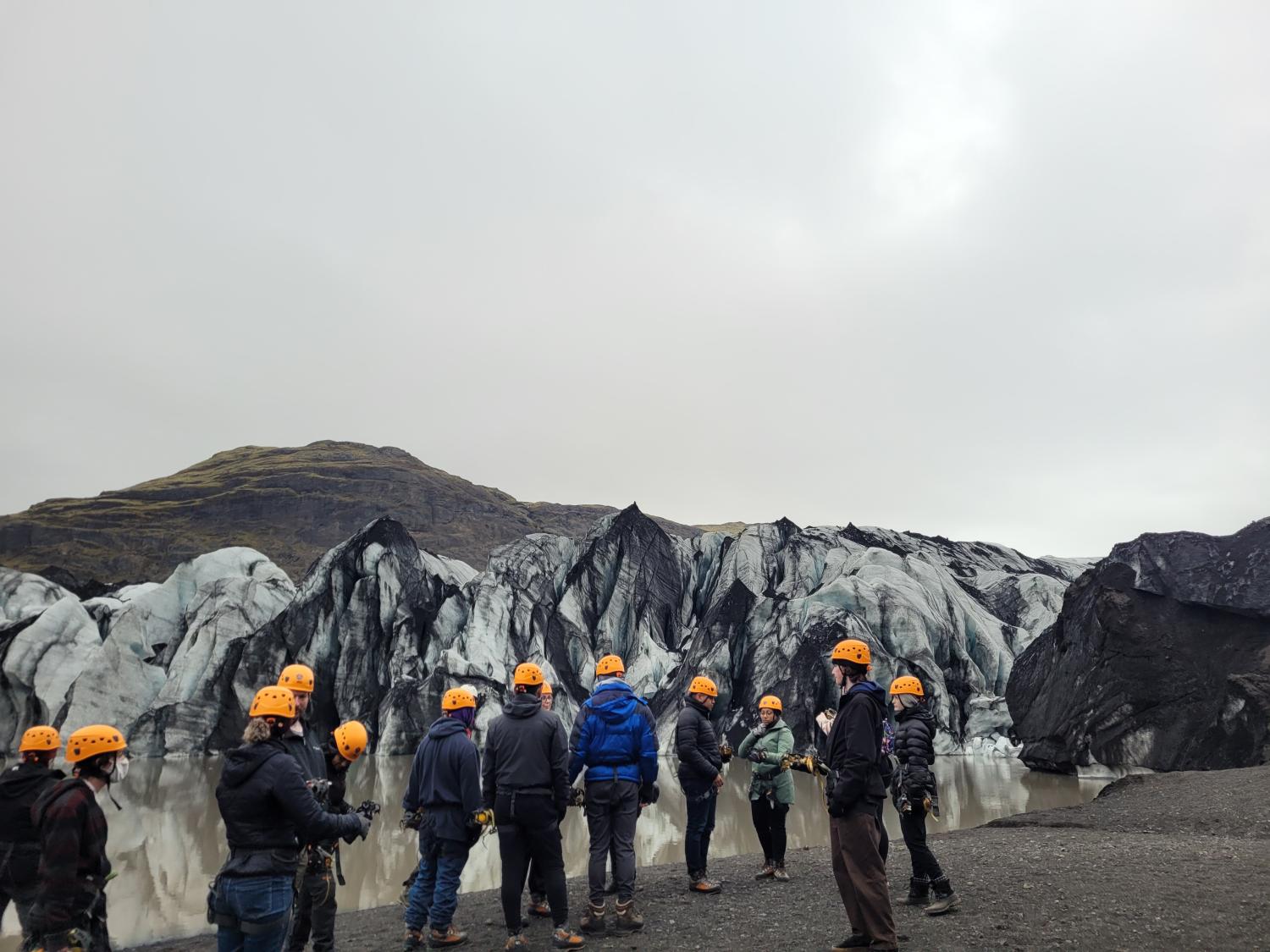 A group of students in hard hats in front of a glacial mountain range