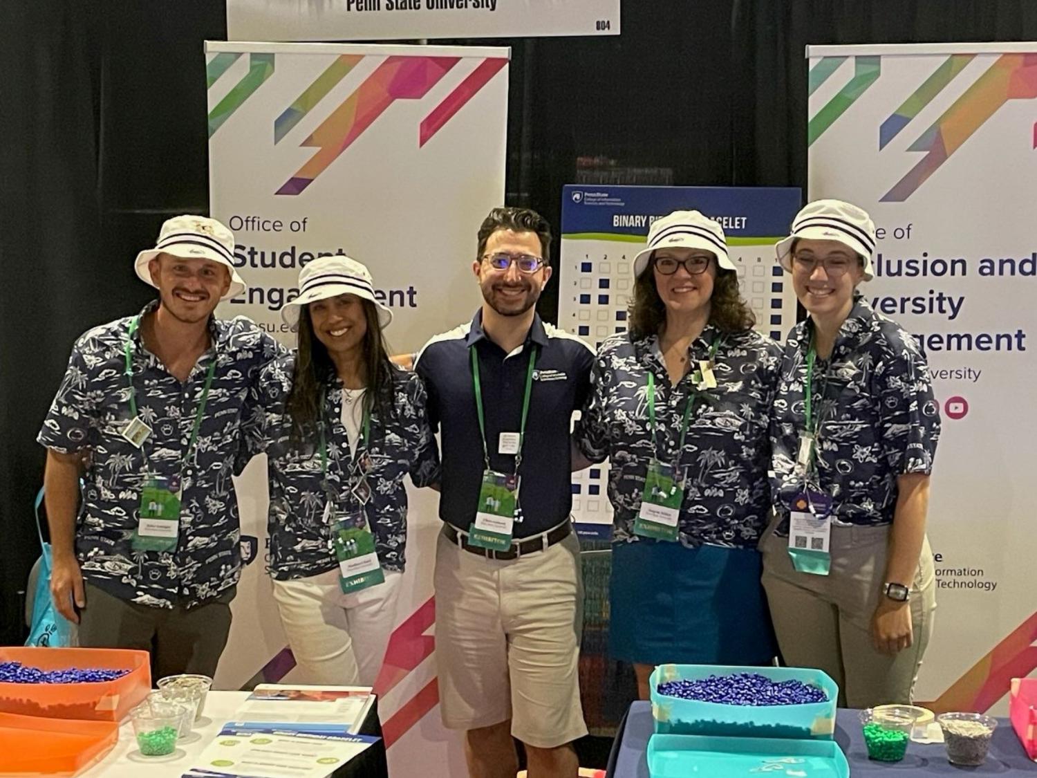 five convention attendees pose at their booth