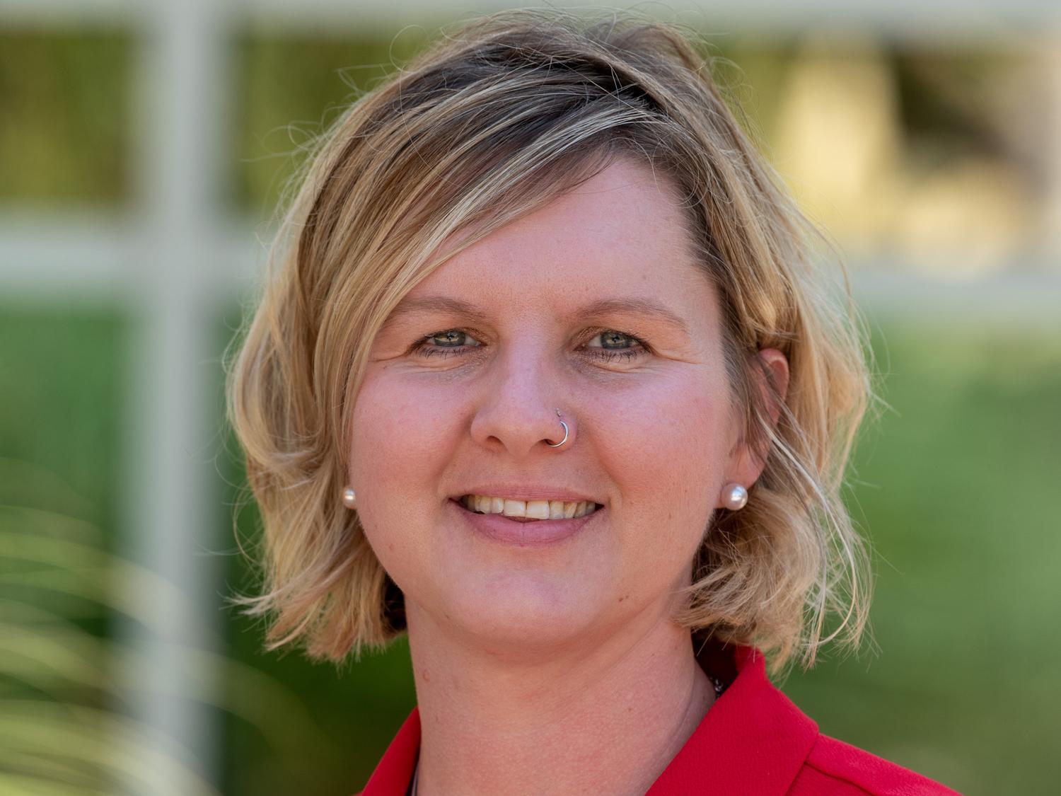A headshot image of Tanae Traister wearing a red jacket.