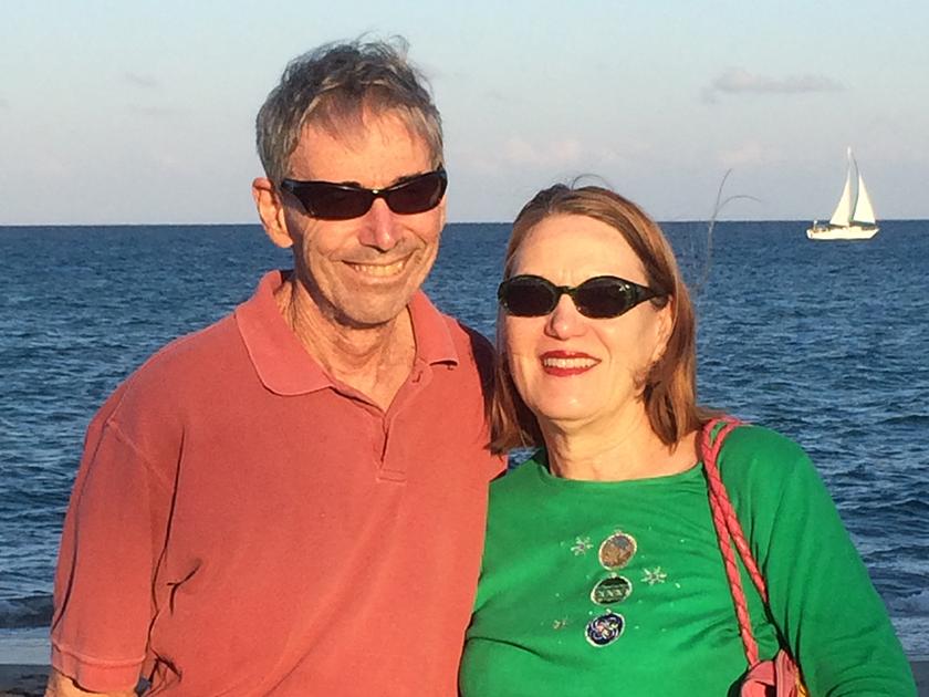 Two people in sunglasses standing in front of a body of water