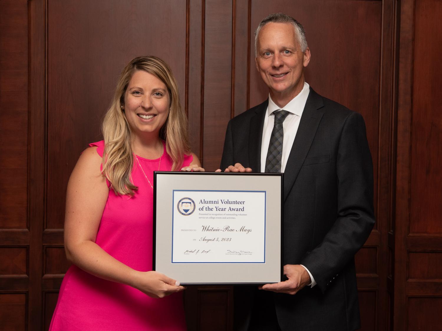 Whitnie-Rae Mays and Michael J. Reed holding a framed certificate between them