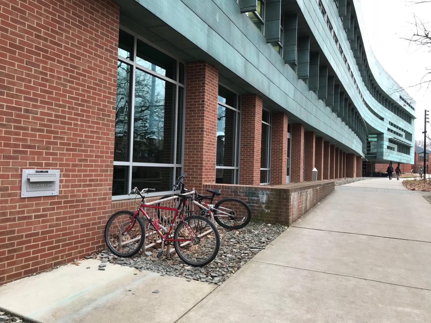 long view exterior of building showing metal book return slot with bicycles in bike rack and side entrance