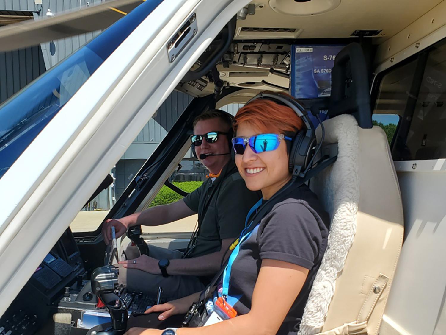 Two people sitting in the cockpit of a helicopter
