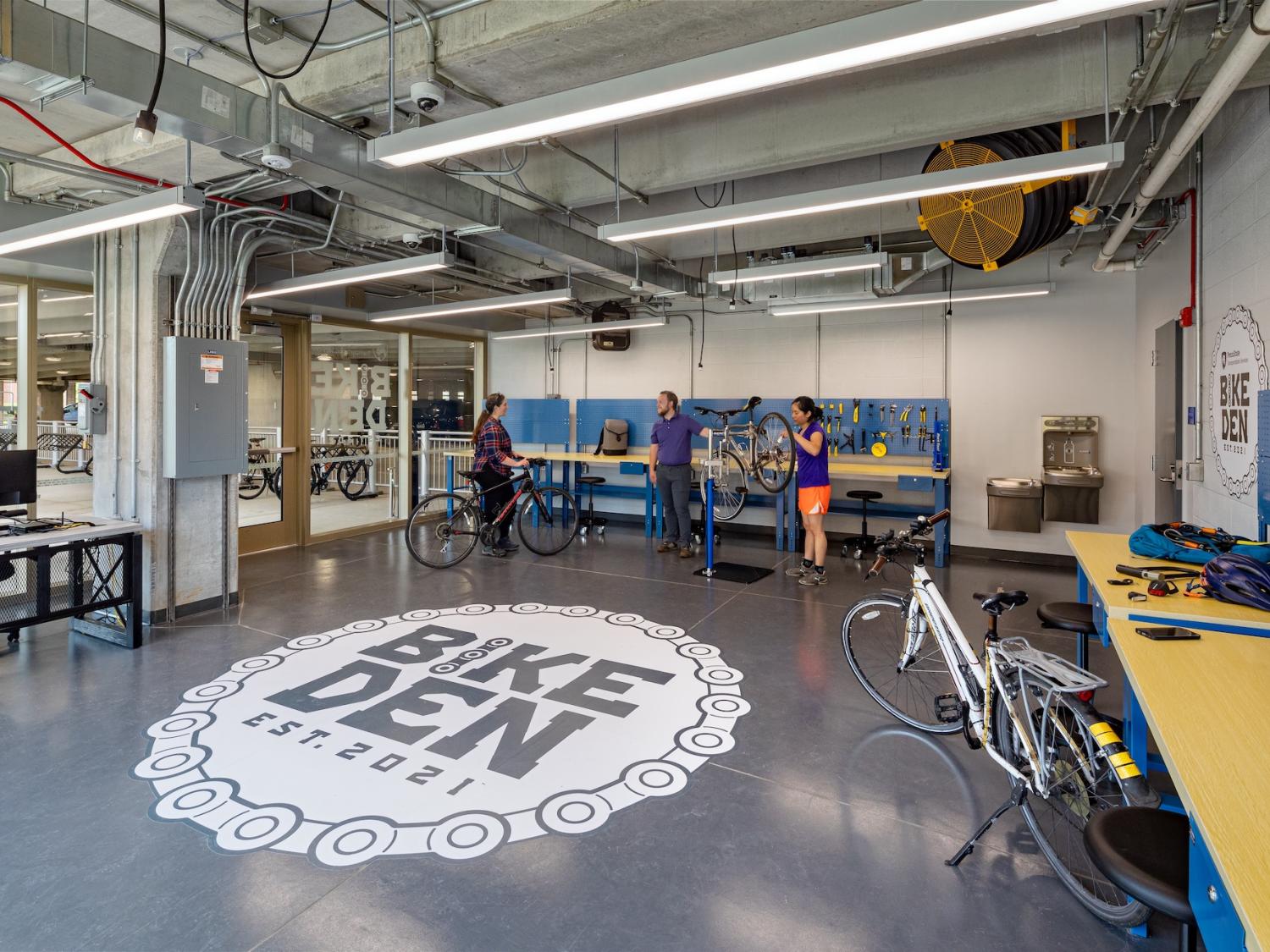 The interior of the Bike Den, showing a large Bike Den logo on the floor and people talking