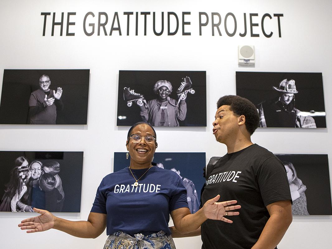 Two people stand in front of a wall of black-and-white photos.