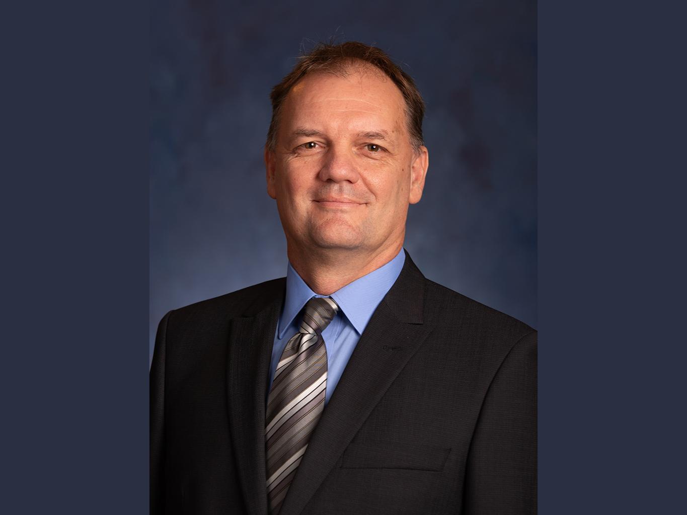 Laszlo Kulcsar wearing a business suit and striped tie, and smiling