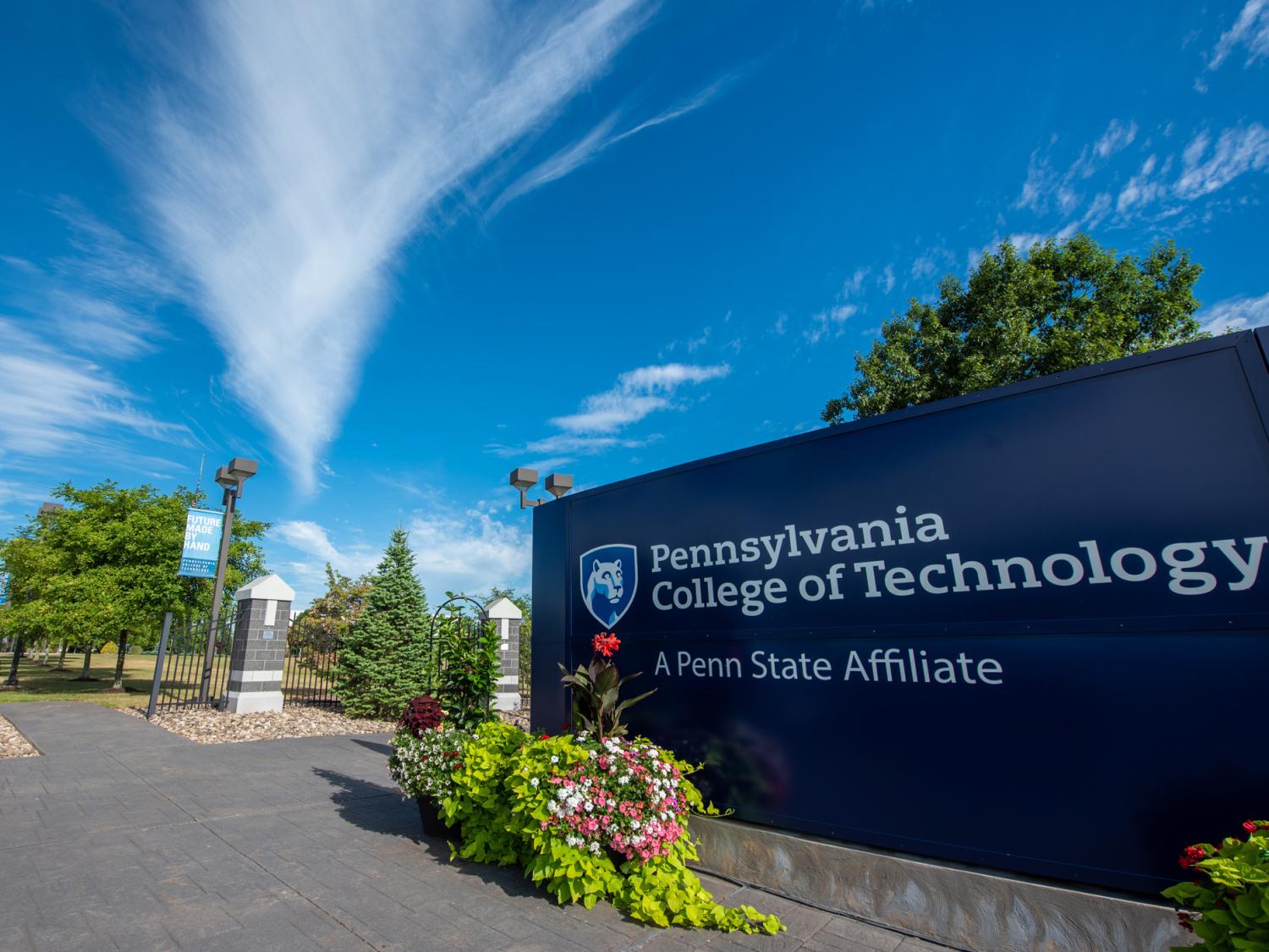 Penn College entrance sign and campus with a blue sky in the background