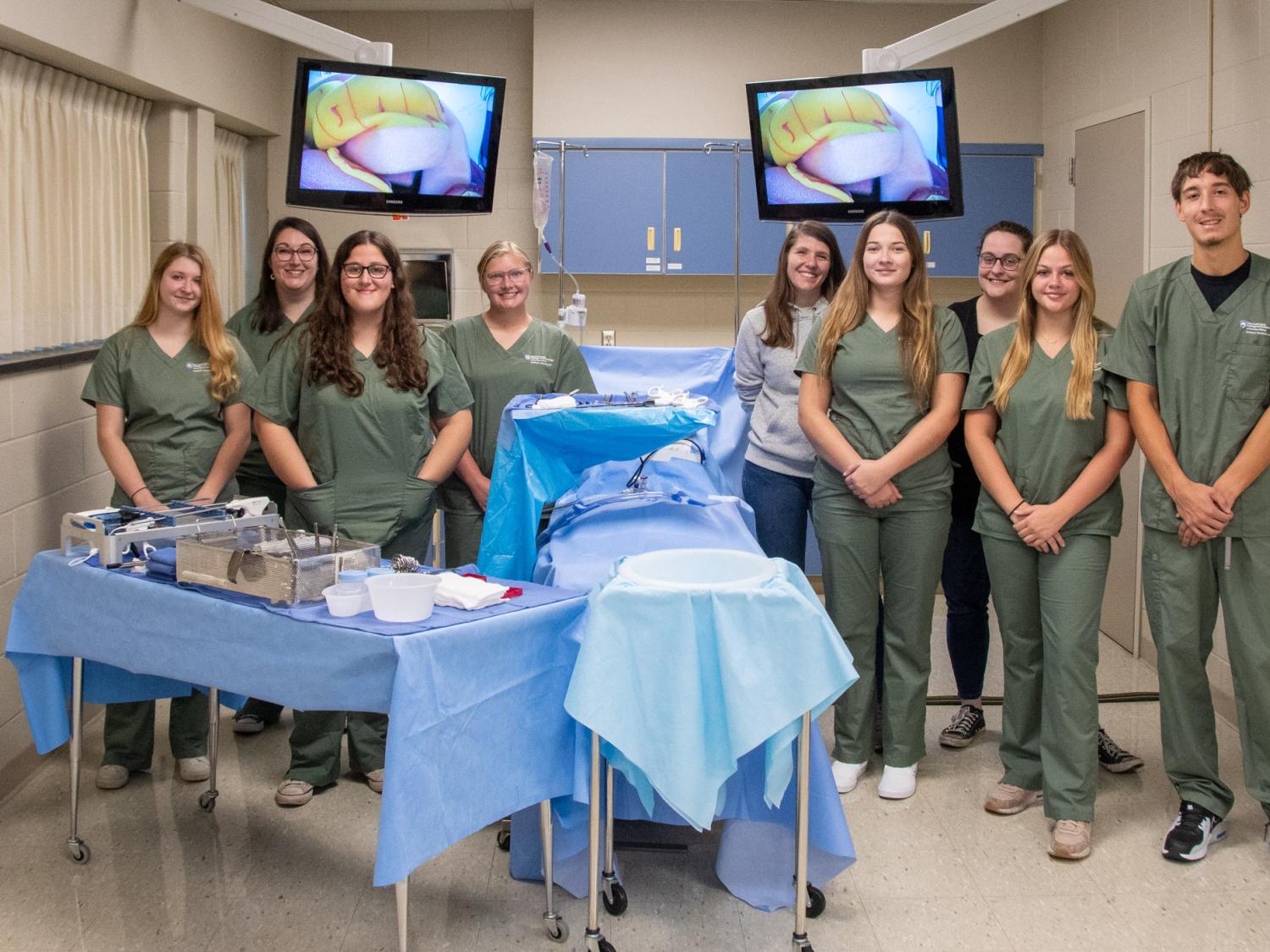 Students in surgical uniform in a surgical demo area