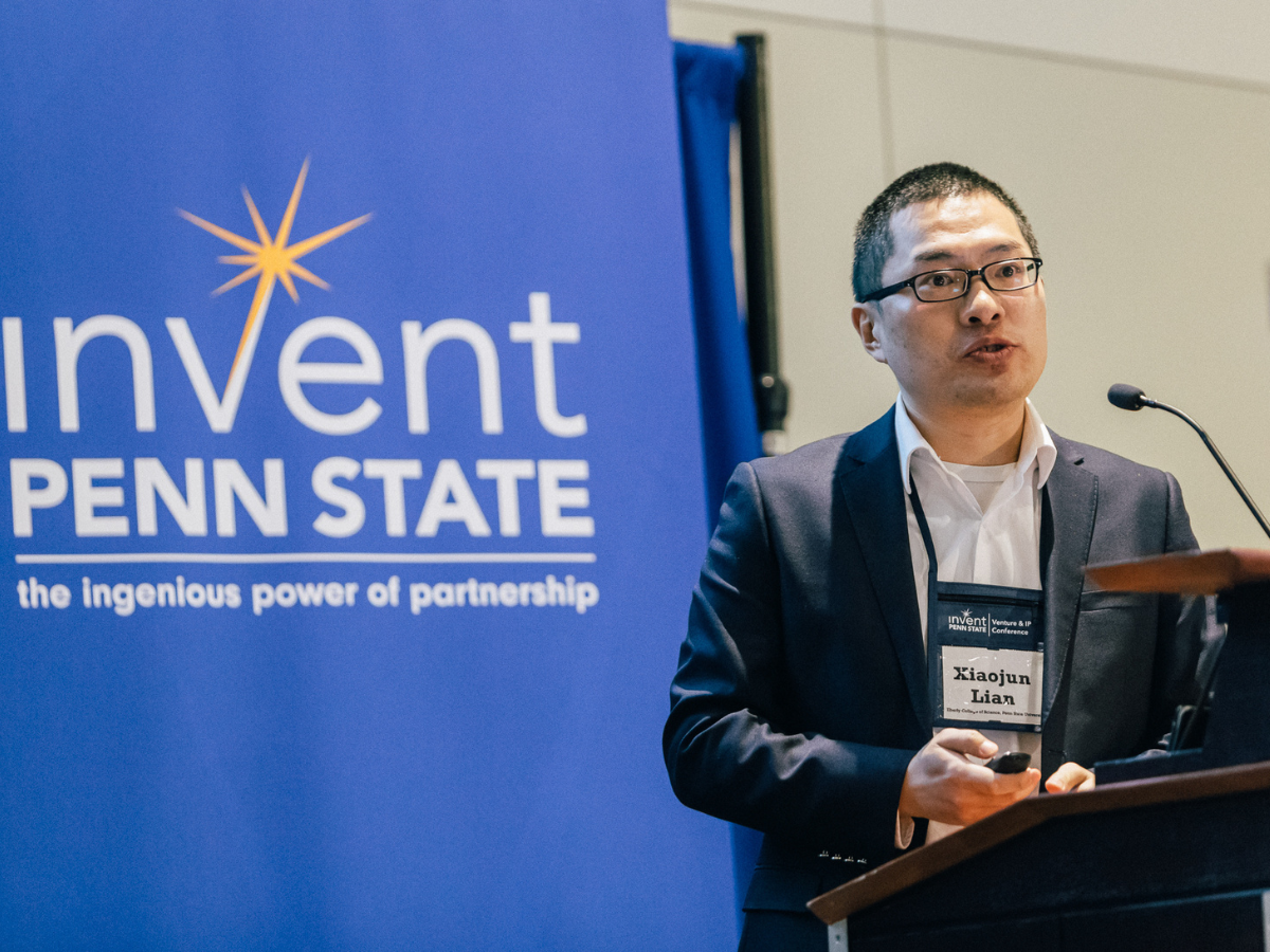 An individual presents standing behind a podium and in front of an Invent Penn State sign
