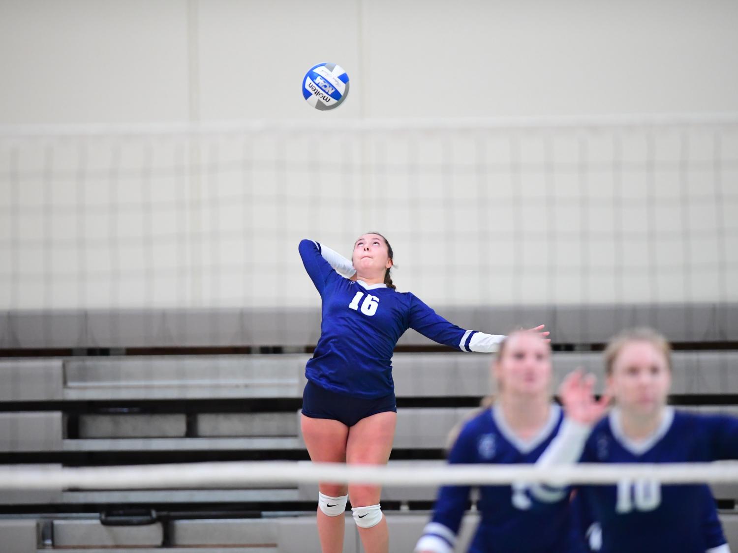 A Penn State Behrend volleyball player jumps while serving the ball.