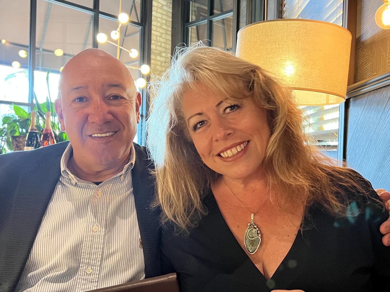 Fernando Montes and Carolyn Inhoffer Montes sitting at a restaurant and smiling at the camera