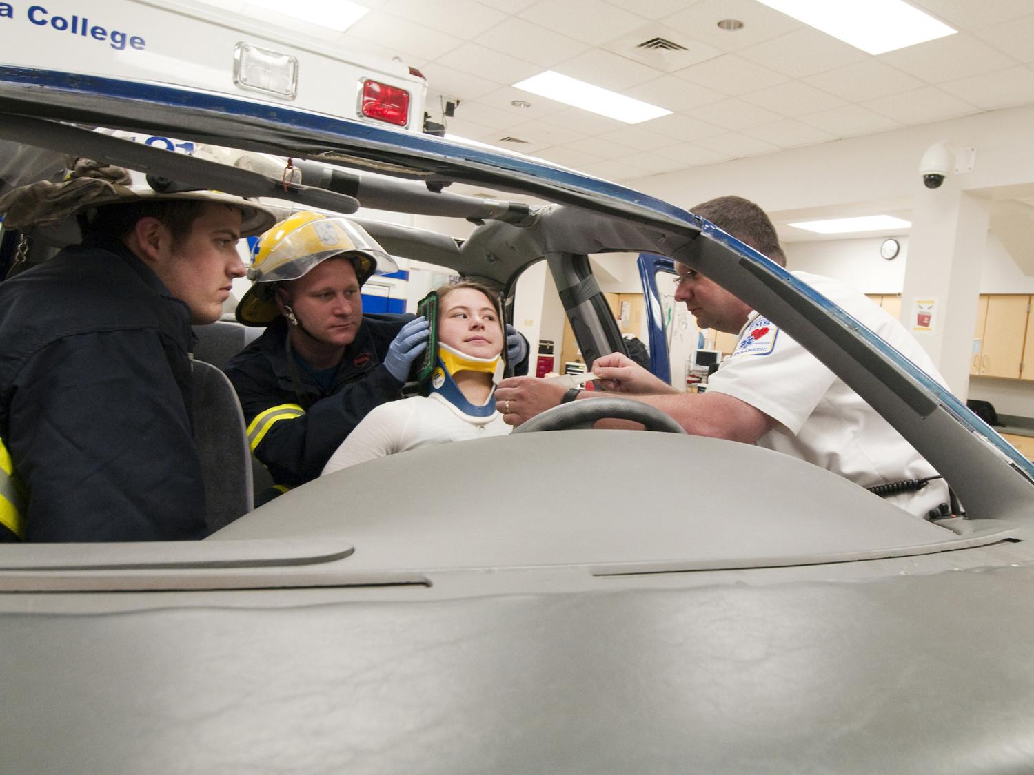 Student EMTs help a person injured in a car accident during a mock training. 