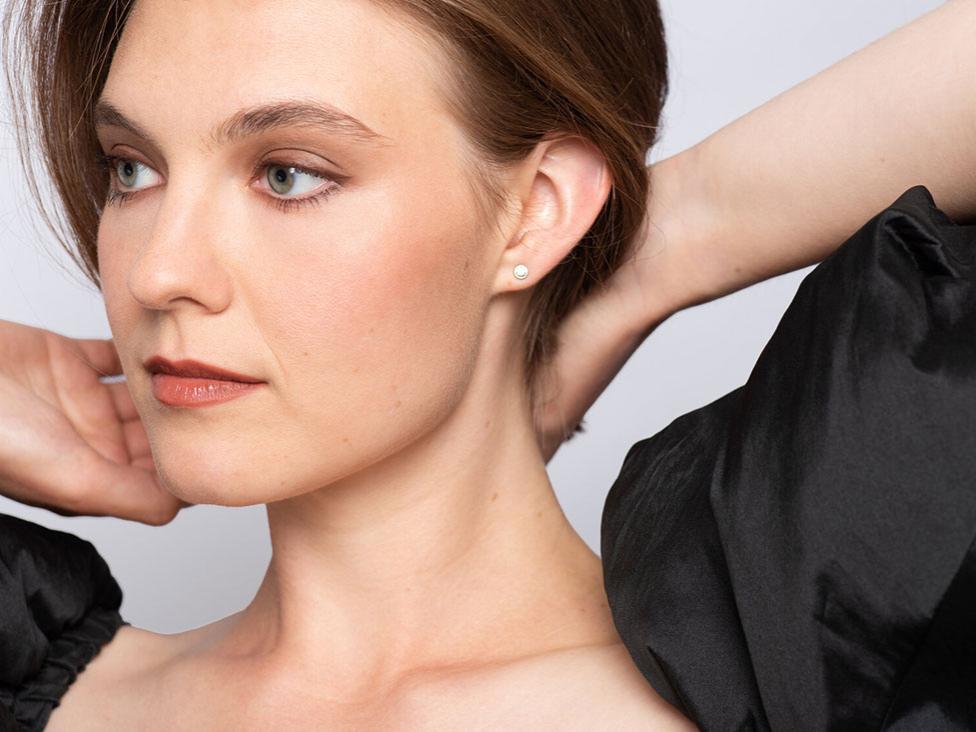 A woman holds her hair back at her neck while she looks off to the side.