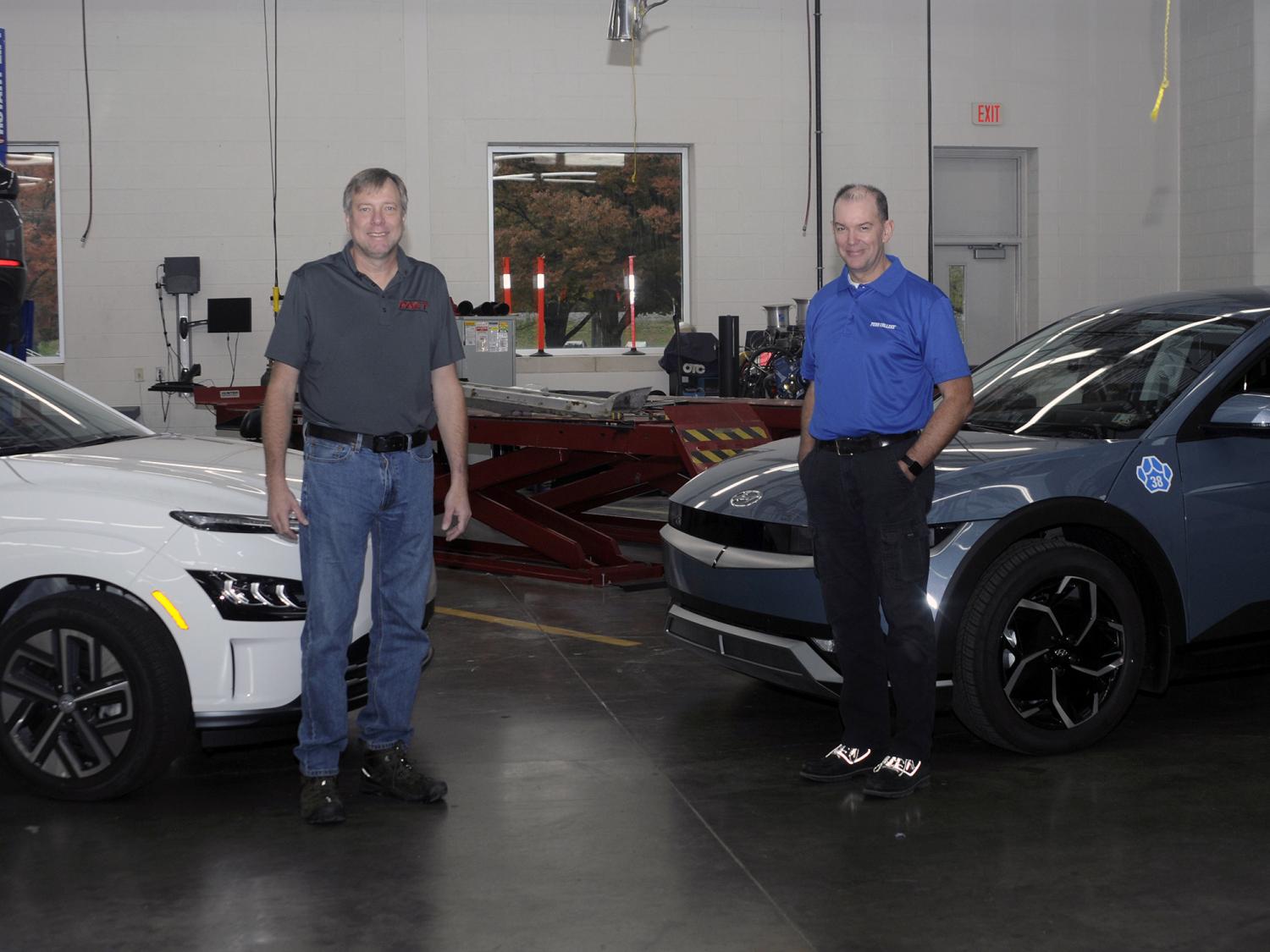 Two people stand with two electric vehicles