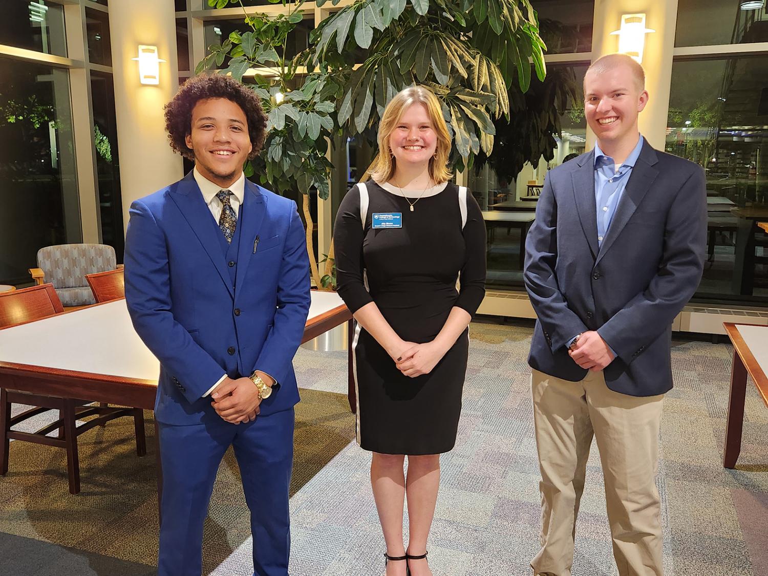 Three people stand posing for a photo