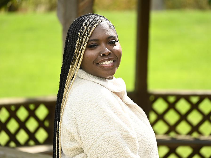 A student seated outside and looking over her shoulder at the camera.
