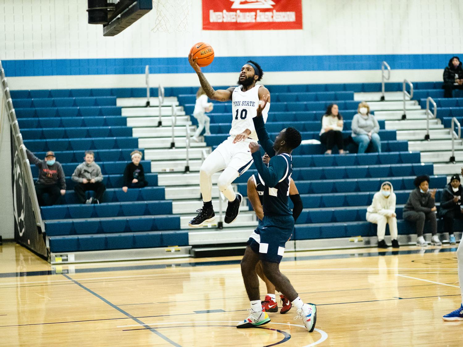 A man with basketball in hand jumping up toward the basket.