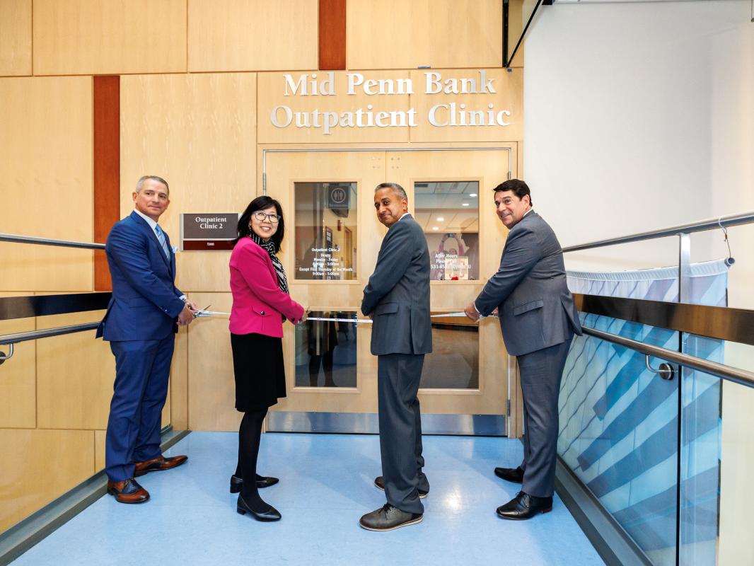 Four people cut the ribbon to dedicate the new name of a healthcare clinic