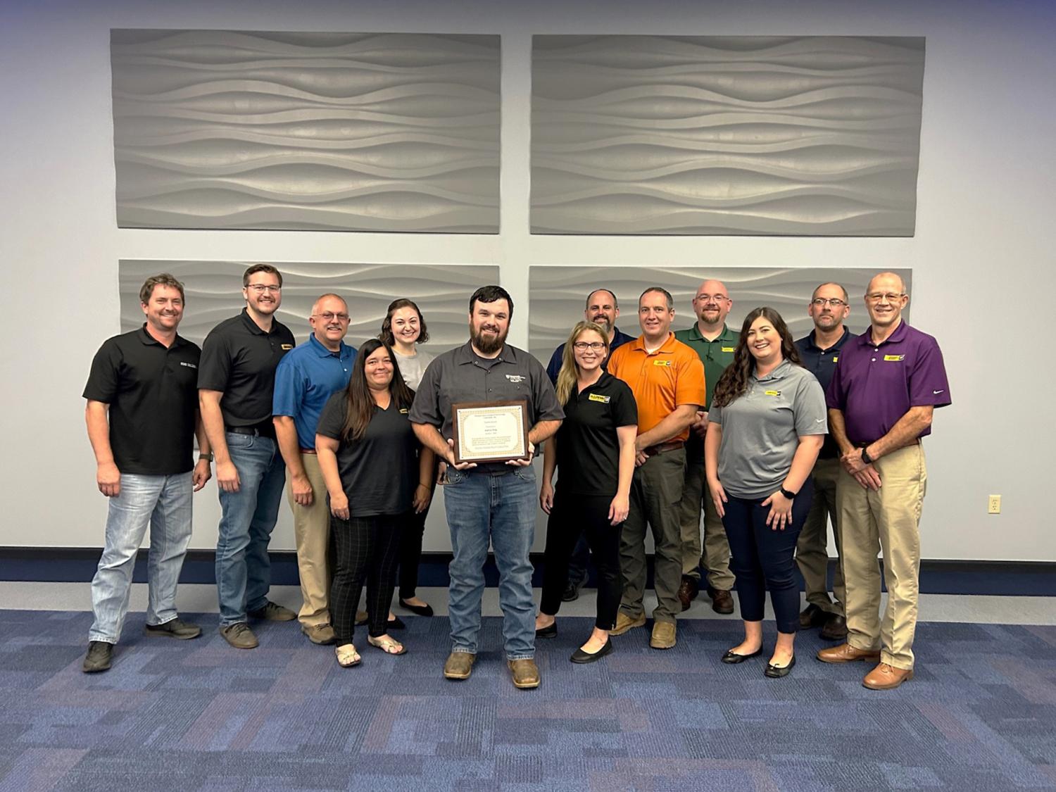 A group of people gather for a photo. Andy King is standing in the middle holding his Pathfinder to Excellence Faculty Award certificate.