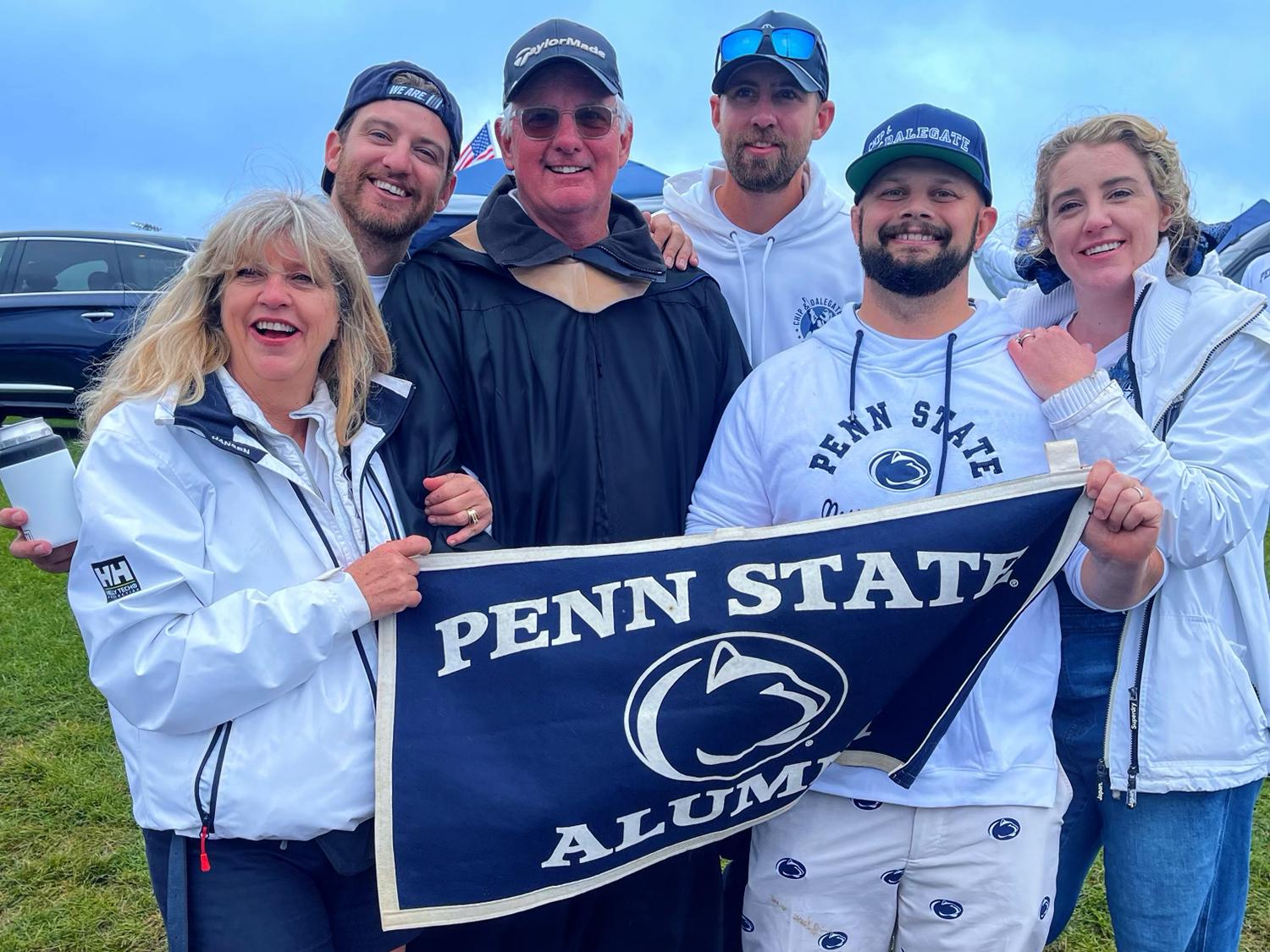 A photo of the Quayle family posing with a banner that reads "Penn State Alumni."