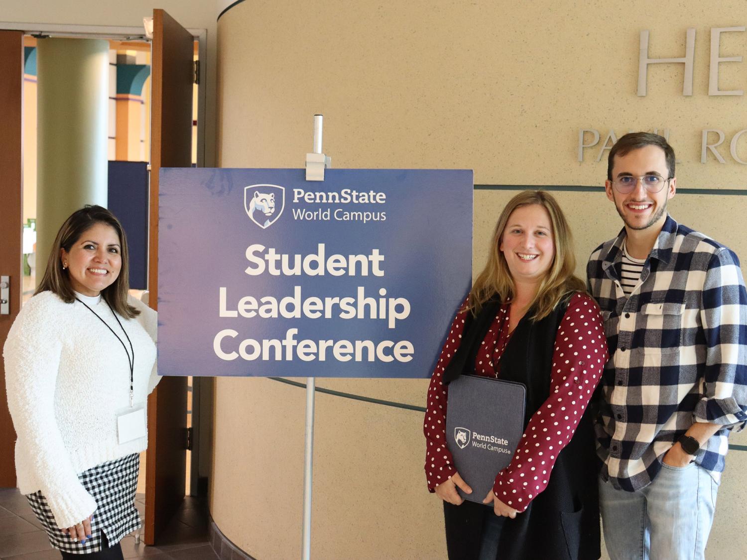 Three students stand around a sign that says Penn State Student Leadership Conference