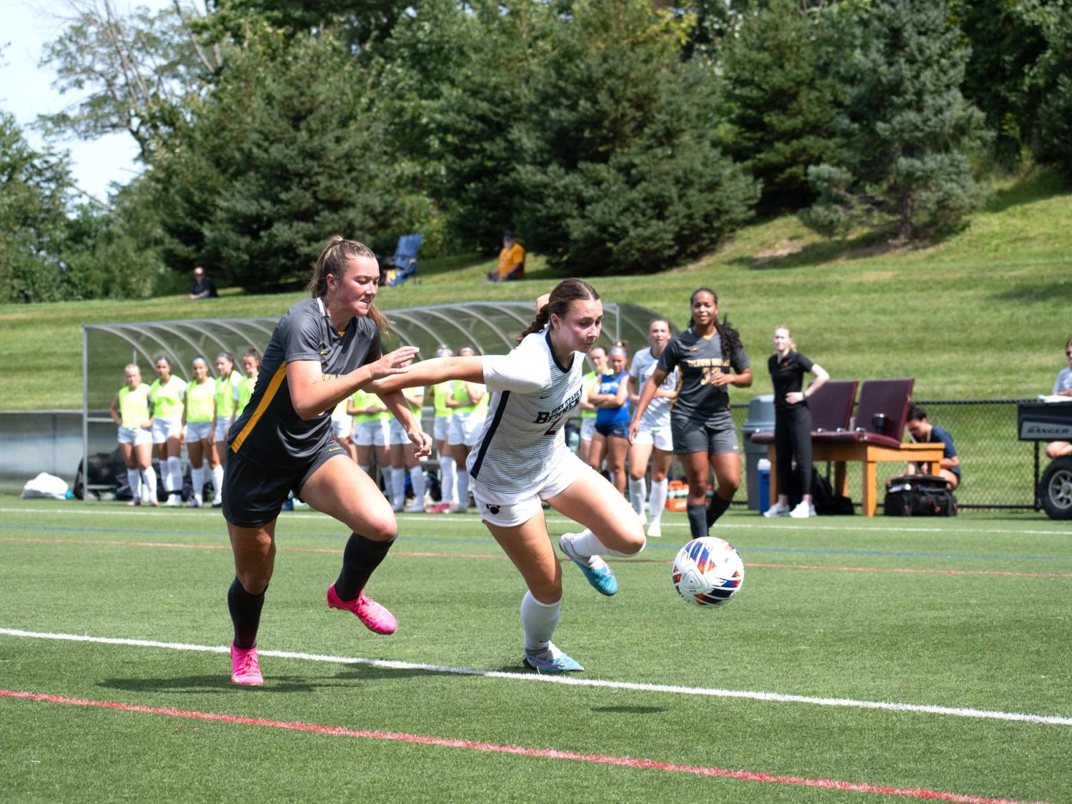 A Penn State Behrend women's soccer player runs past a defender.