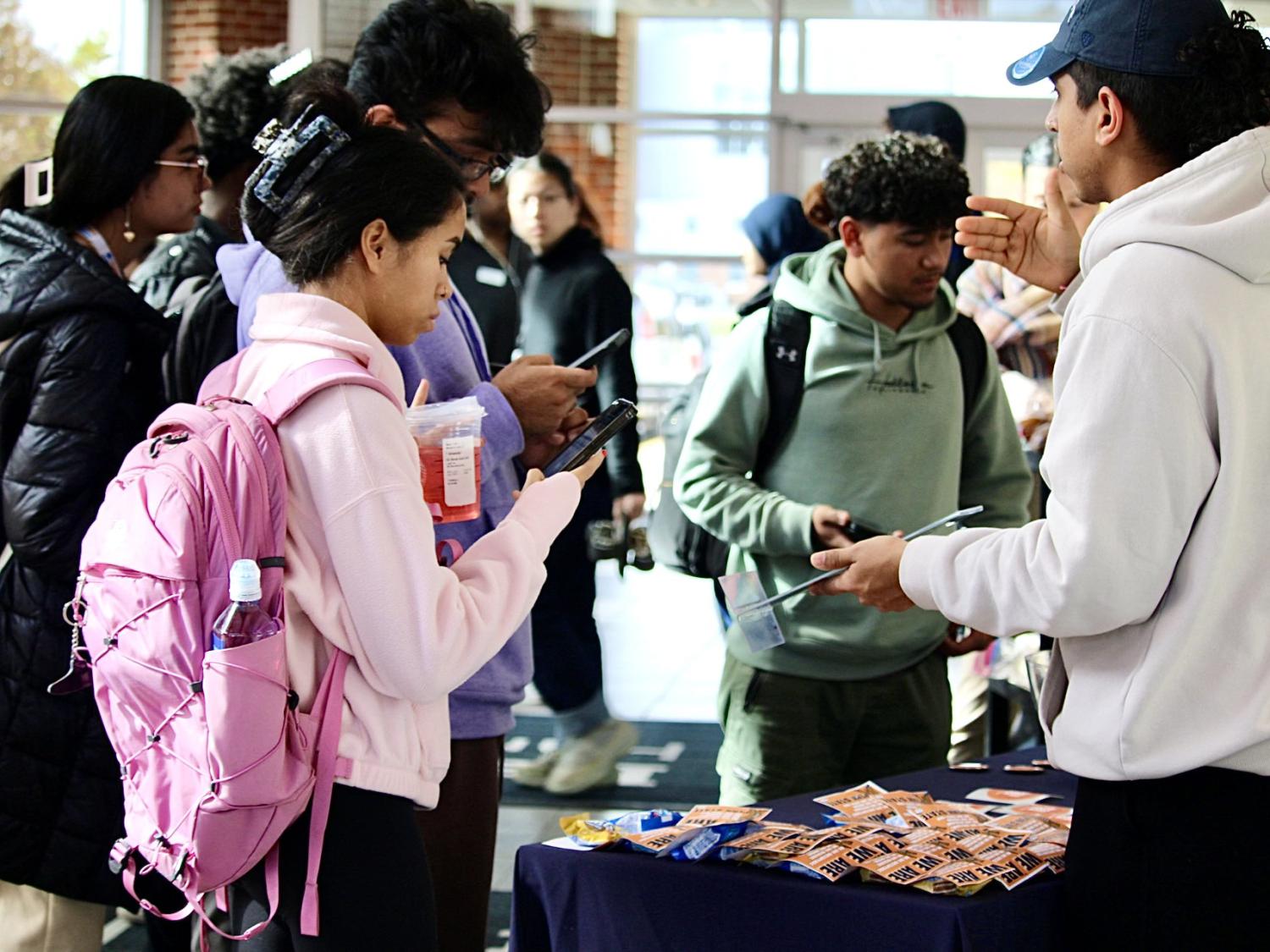 Students approach an information table during a first-gen student event in Olmsted Building atrium