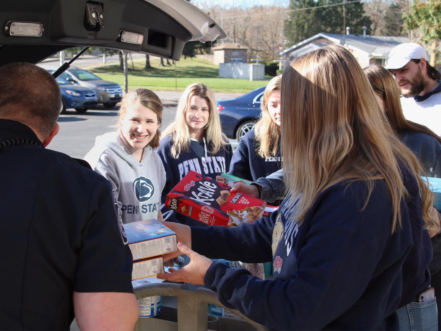 Students moving food and supplies into the back of a police vehicle