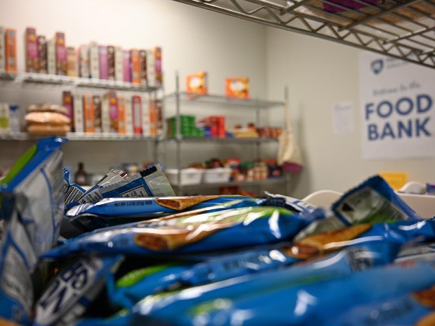 A close-up of granola bars with other food on shelves in the background