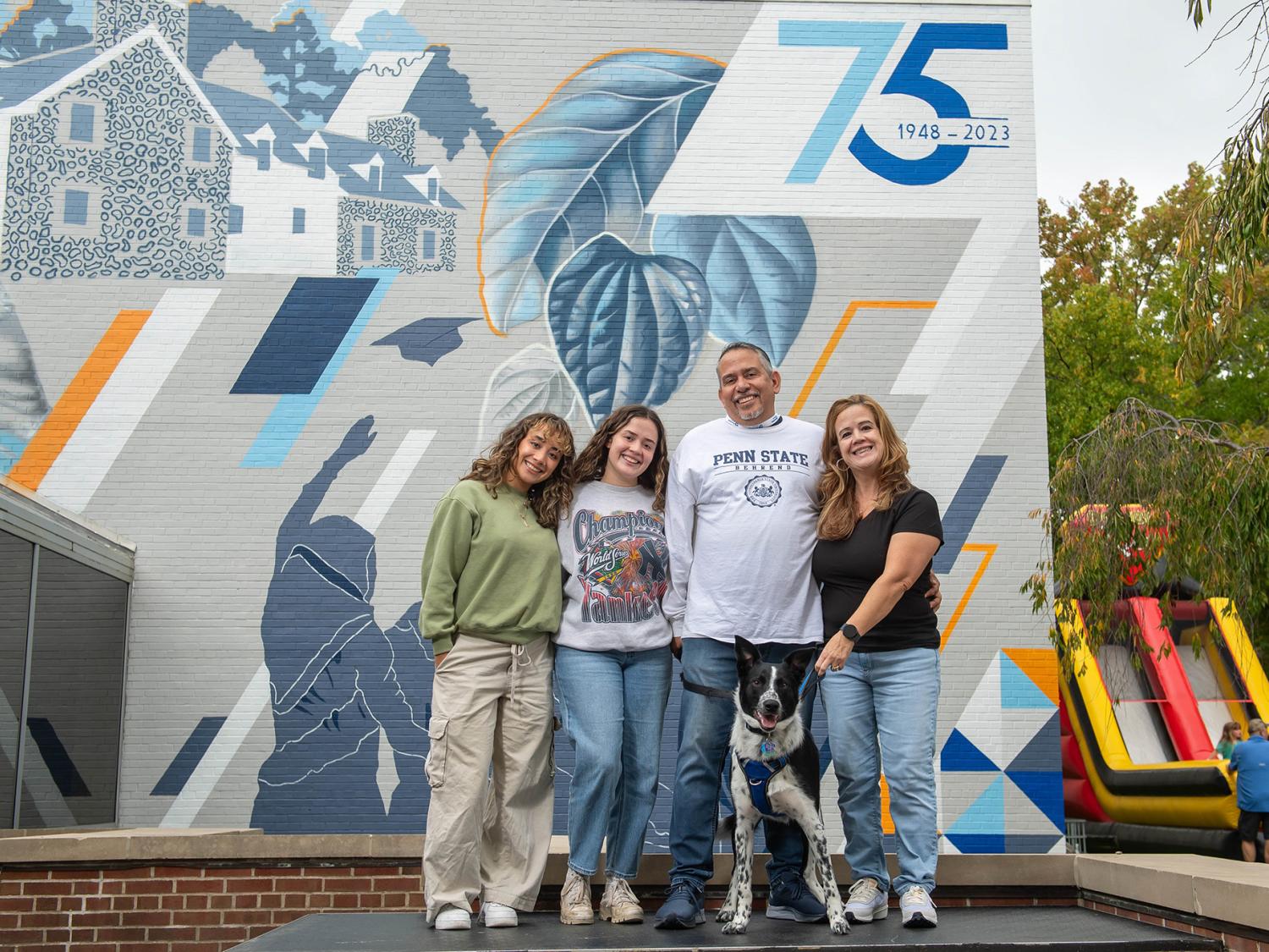Guests pose in front of the new "Behrend Pride" mural at Penn State Behrend.