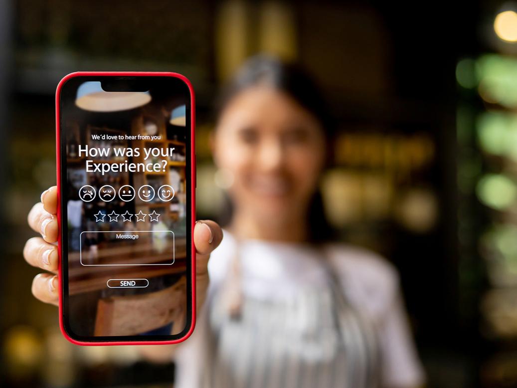 Waitress displays an app to rate an experience at a restaurant