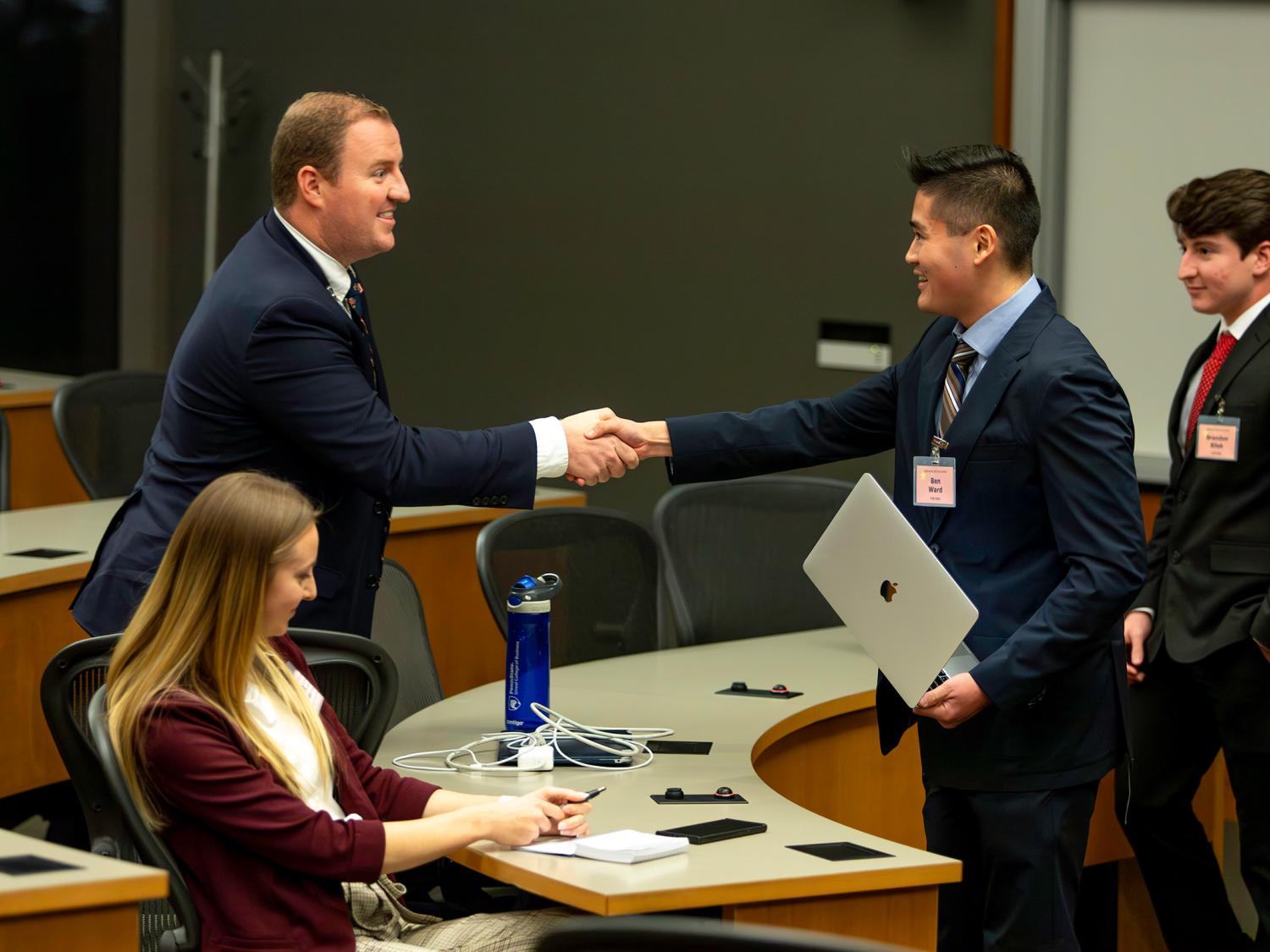 SIA students Barrett Beaumont (left - Team United States) and Ben Ward (Team China) shake hands while negotiating during the USAWC crisis simulation.