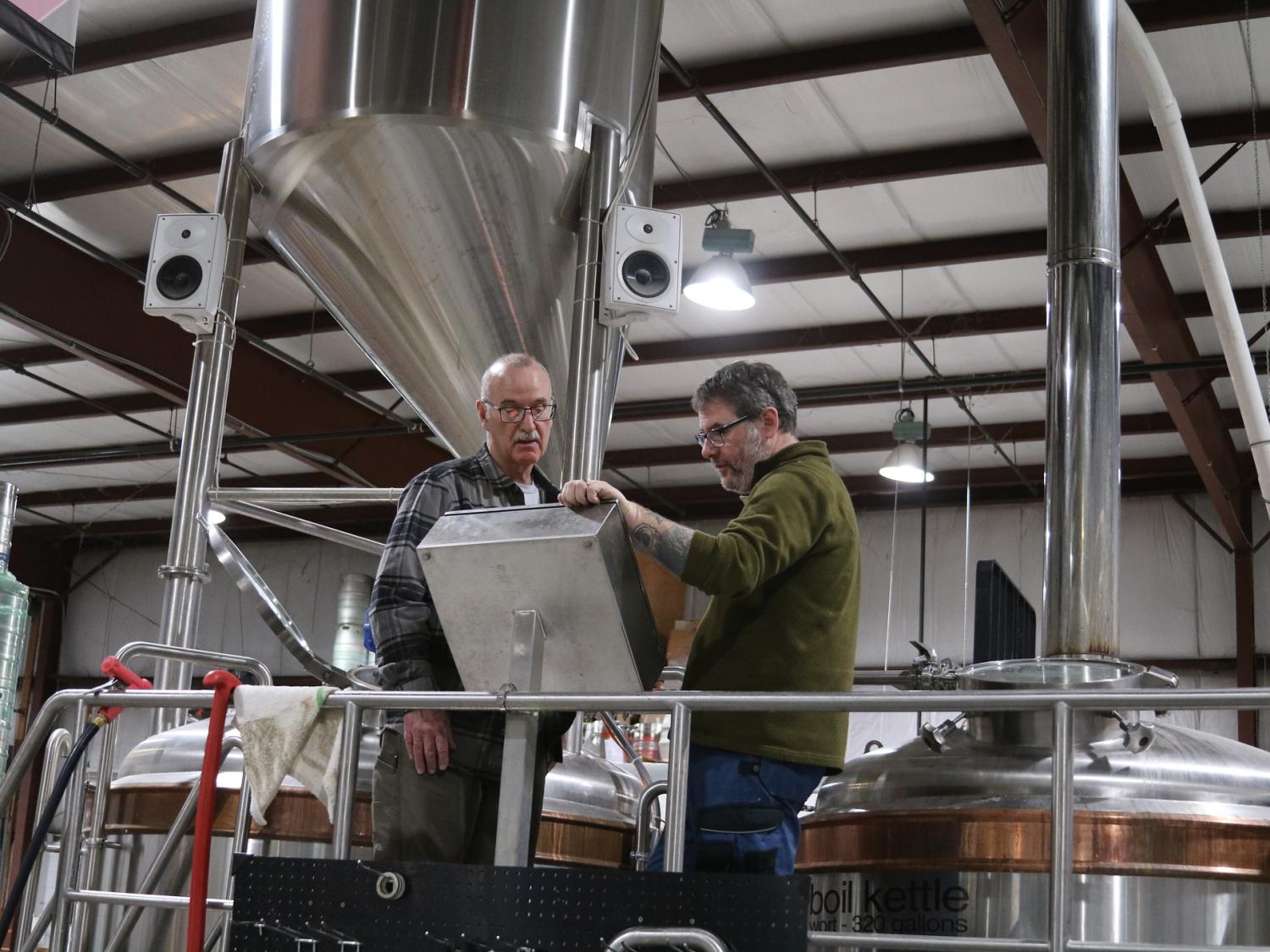 Two men in brewery looking thoughtful at screen