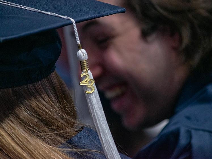A class of 23 tassel dangles in front of smiling graduate faces