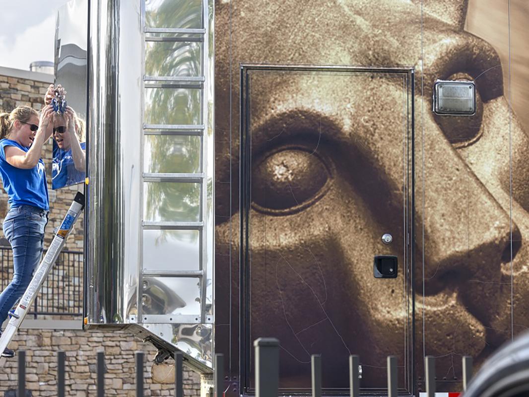 A woman stands at the rear of a truck on a small ladder.
