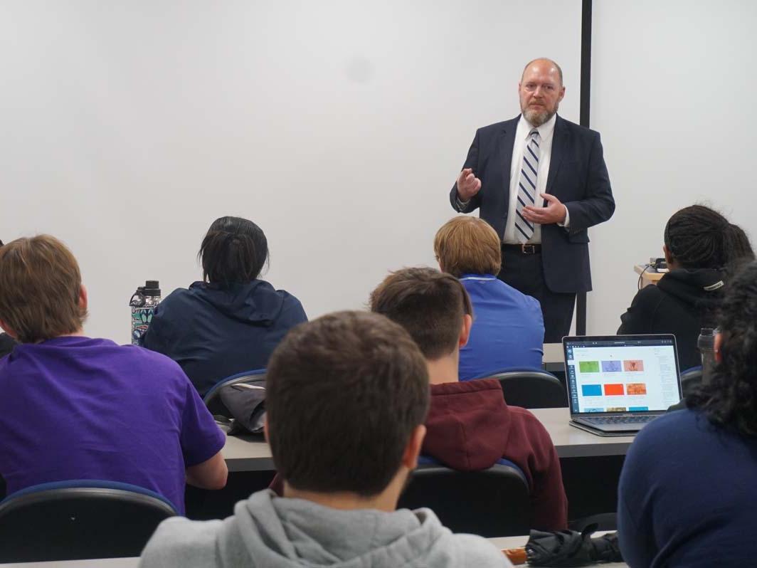 Man in a suit speaking to students in a classroom