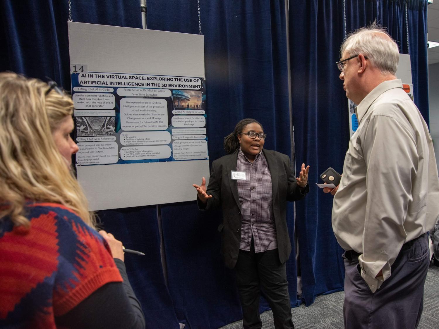 Three people talk in front of a research poster