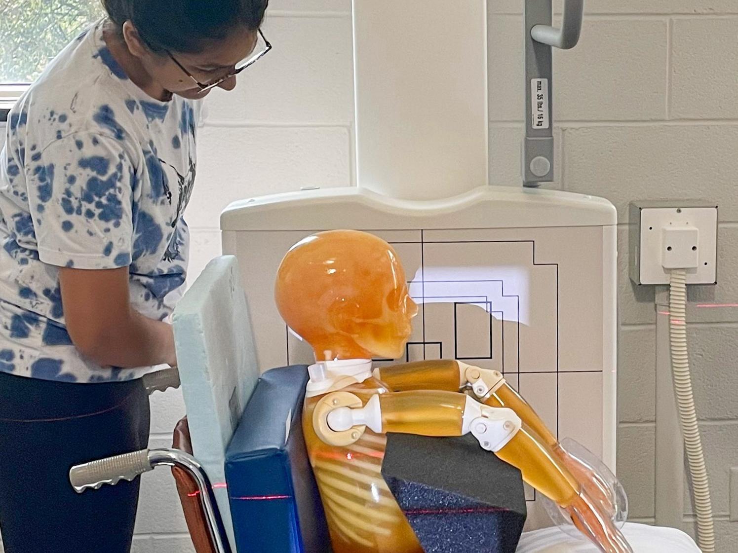 A radiography student oversees the chest X-ray of a pediatric phantom.