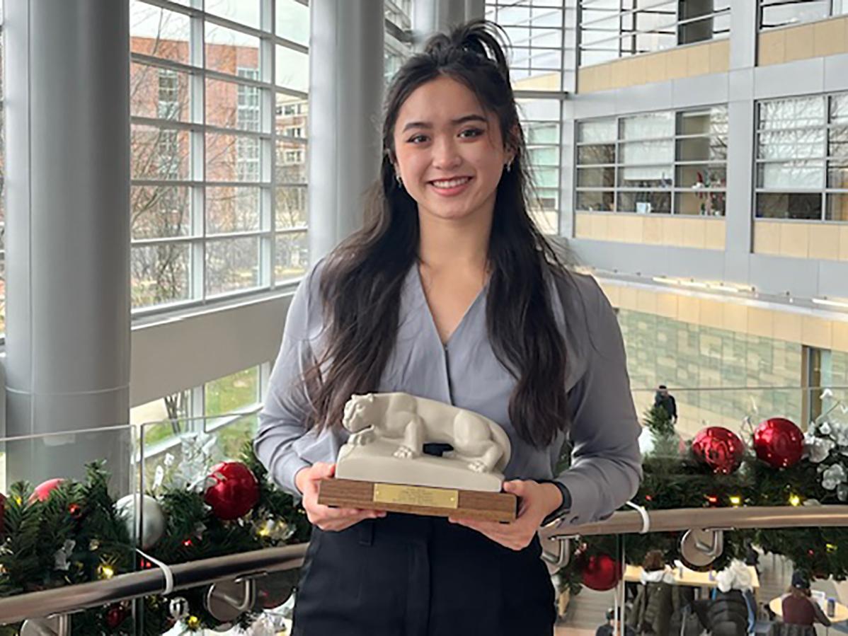 A photo of Sophie Darkes holding a Nittany Lion shrine replica in the Business Building atrium