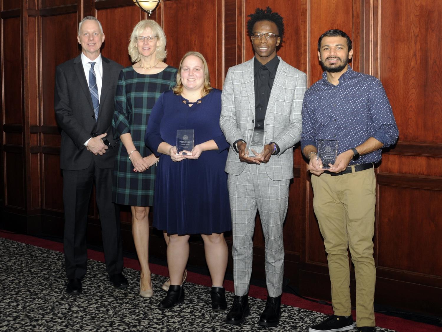 Five people stand in a row at an awards ceremony