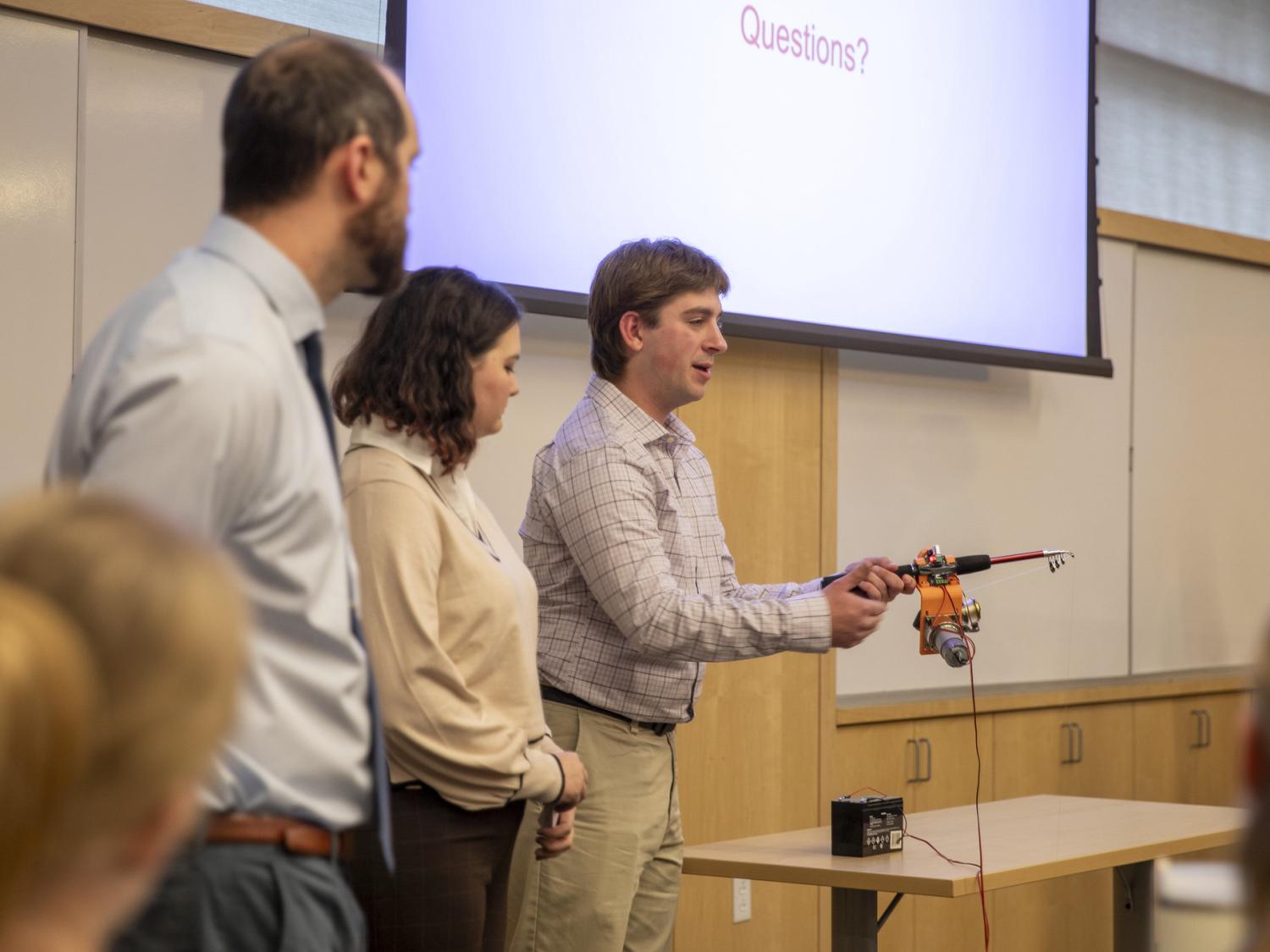 Male student showcases adaptive fishing rod.